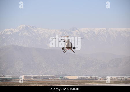 Ein MD 530F Cayuse Krieger leichte Kampfhubschrauber der Afghanischen Luftwaffe fliegt über militärische Flughafen Kabul, Afghanistan, vor der Hindu Kush Bergkette am Horizont. Stockfoto