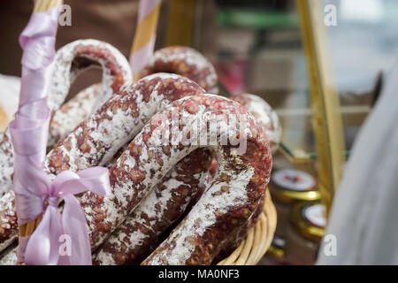 Close-up Weidenkorb mit typischen italienischen Salami auf Markt, traditionelle Köstlichkeiten. Gastronomische Geschenk für Gourmets. Reale Szene in superm Stockfoto
