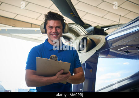 Portrait der männlichen Aero Ingenieur mit Zwischenablage Durchführung auf Helikopter im Hangar prüfen Stockfoto