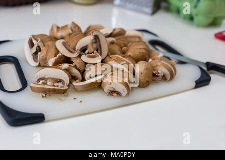 Ein Haufen von geschnittenen Kastanie Champignons (Agaricus bisporus) auf einem weißen Schneidebrett Stockfoto