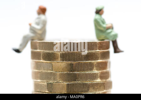 Gender Gleichstellung Konzept Bild von Mann und Frau auf einem Stapel Pfund Münzen Stockfoto