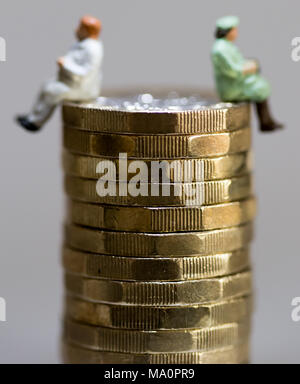 Gender Gleichstellung Konzept Bild von Mann und Frau auf einem Stapel Pfund Münzen Stockfoto