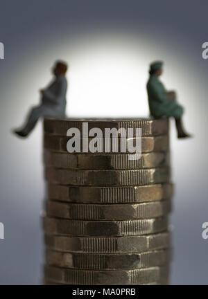 Gender Gleichstellung Konzept Bild von Mann und Frau auf einem Stapel Pfund Münzen Stockfoto