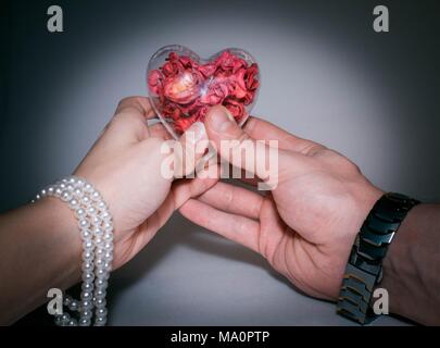 Rotes Herz in Frauen und Männern die Hände auf hellen Hintergrund Stockfoto