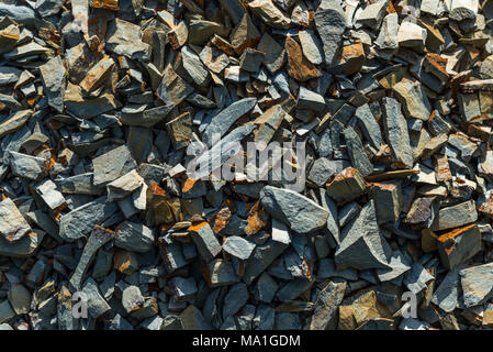 Oberfläche aus kleinen Steinen in der Sonne, die als Hintergrund verwendet werden kann. Stockfoto