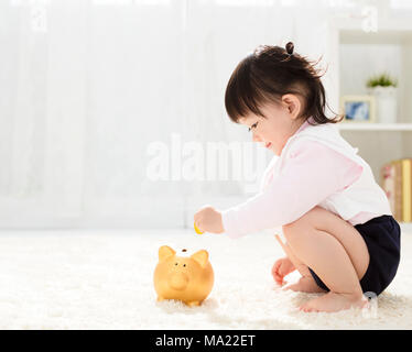 Baby girl Einfügen einer Münze in sparschwein Stockfoto