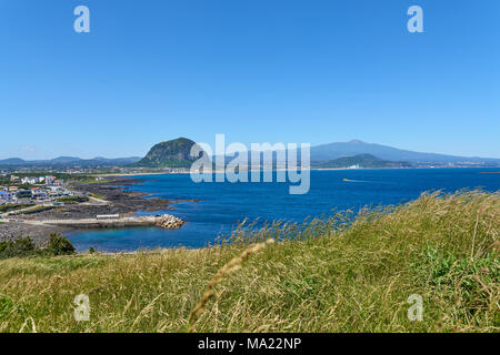 Landschaft von Sagye-ri Dorf und der südwestlichen Küste der Insel Jeju mit Sanbangsan und Hallasan Berg, von Olle trail Nr. 10 am Songaksan gesehen. Stockfoto