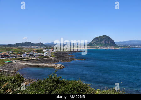 Landschaft von Sagye-ri Dorf und der südwestlichen Küste der Insel Jeju mit Sanbangsan und Hallasan Berg, von Olle trail Nr. 10 am Songaksan gesehen. Stockfoto