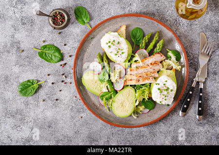 Gesundes Frühstück. Pochierte Eier auf Toast mit Avocado, Spargel und Hähnchen Filet vom Grill. Ansicht von oben Stockfoto