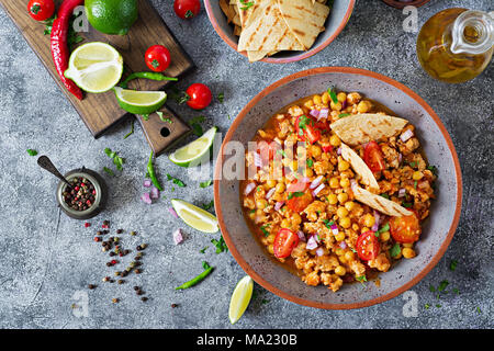 Chili con Carne der Türkei mit Kichererbsen, serviert mit Nachos. Chili mit Fleisch, Nachos, Kalk, Paprika. Mexikanische/Texas traditionelles Essen. Ansicht von oben Stockfoto