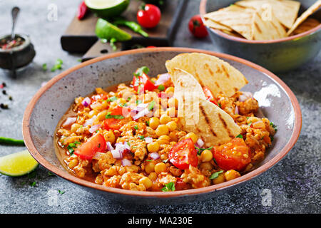 Chili con Carne der Türkei mit Kichererbsen, serviert mit Nachos. Chili mit Fleisch, Nachos, Kalk, Paprika. Mexikanische/Texas traditionelles Essen. Stockfoto