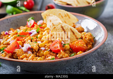 Chili con Carne der Türkei mit Kichererbsen, serviert mit Nachos. Chili mit Fleisch, Nachos, Kalk, Paprika. Mexikanische/Texas traditionelles Essen. Stockfoto