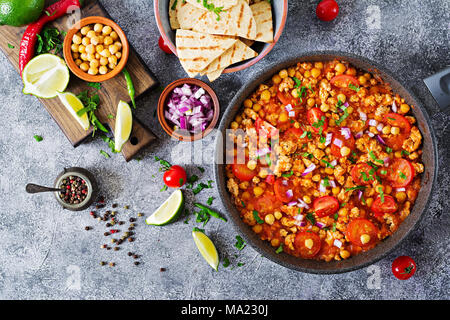 Chili con Carne der Türkei mit Kichererbsen, serviert mit Nachos. Chili mit Fleisch, Nachos, Kalk, Paprika. Mexikanische/Texas traditionelles Essen. Ansicht von oben Stockfoto