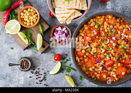 Chili con Carne der Türkei mit Kichererbsen, serviert mit Nachos. Chili mit Fleisch, Nachos, Kalk, Paprika. Mexikanische/Texas traditionelles Essen. Ansicht von oben Stockfoto