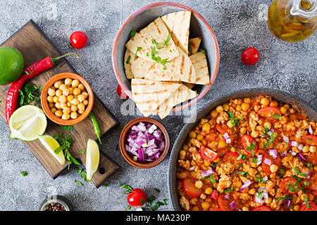 Chili con Carne der Türkei mit Kichererbsen, serviert mit Nachos. Chili mit Fleisch, Nachos, Kalk, Paprika. Mexikanische/Texas traditionelles Essen. Ansicht von oben Stockfoto