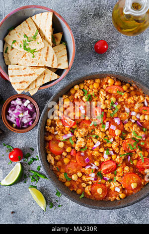 Chili con Carne der Türkei mit Kichererbsen, serviert mit Nachos. Chili mit Fleisch, Nachos, Kalk, Paprika. Mexikanische/Texas traditionelles Essen. Ansicht von oben Stockfoto