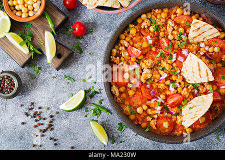 Chili con Carne der Türkei mit Kichererbsen, serviert mit Nachos. Chili mit Fleisch, Nachos, Kalk, Paprika. Mexikanische/Texas traditionelles Essen. Ansicht von oben Stockfoto