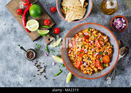 Chili con Carne der Türkei mit Kichererbsen, serviert mit Nachos. Chili mit Fleisch, Nachos, Kalk, Paprika. Mexikanische/Texas traditionelles Essen. Ansicht von oben Stockfoto