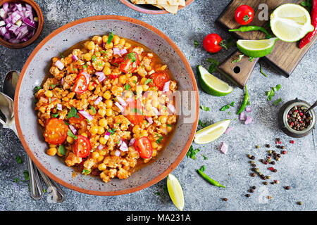 Chili con Carne der Türkei mit Kichererbsen, serviert mit Nachos. Chili mit Fleisch, Nachos, Kalk, Paprika. Mexikanische/Texas traditionelles Essen. Ansicht von oben Stockfoto