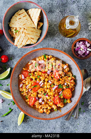 Chili con Carne der Türkei mit Kichererbsen, serviert mit Nachos. Chili mit Fleisch, Nachos, Kalk, Paprika. Mexikanische/Texas traditionelles Essen. Ansicht von oben Stockfoto
