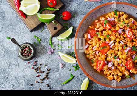 Chili con Carne der Türkei mit Kichererbsen, serviert mit Nachos. Chili mit Fleisch, Nachos, Kalk, Paprika. Mexikanische/Texas traditionelles Essen. Ansicht von oben Stockfoto