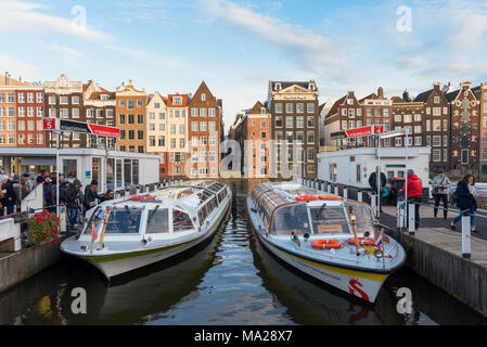 Zwei der beliebtesten Touristenattraktionen von Amsterdam Sightseeing Boote laden und die Fahrgäste an den Piers von Damrak Straße, Amsterdam entladen. Stockfoto