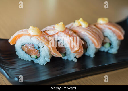 Gegrillter Lachs Sushi Roll, japanisches Essen Stil auf Schwarz Keramik Teller. Stockfoto