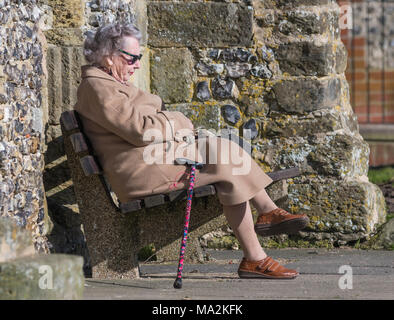 Ältere Dame auf einer Parkbank mit einem Rest in Großbritannien. Stockfoto