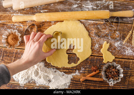 Das Mädchen Schnitte aus dem Teig curly Cookies. Ostern Cookies auf einer hölzernen Hintergrund. Schönen still-Leben mit Cookie. p. Stockfoto