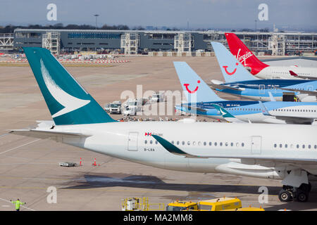 Verschiedene Schwanzflosse von Verkehrsflugzeugen mit Cathay Pacific, Tui und Jungfrau im Terminal 2 im Flughafen Manchester geparkt Stockfoto