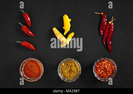 Kochen mit frischen Gewürze mit drei kleinen Schüsseln von Spice auf einem Schwarzen Tisch Ansicht von oben mit Copyspace. Immer noch leben. Flach. Ansicht von oben. Stockfoto