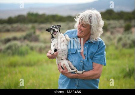 Ein lächelndes, Senior woman holding Ihr glückliches, Ratte Terrier Hund. Stockfoto