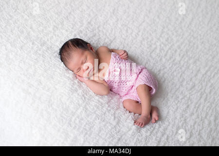 Porträt eines Schlafenden, 7 Tage altes Baby Mädchen mit einem gestricken, rosa Strampelanzug. Stockfoto