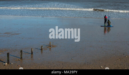 Zwei Personen in geeigneter Kleidung angeln mit Linie und Stab vom Strand in Seaham im County Durham Stockfoto