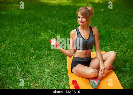 Fitness Mädchen im Park und in verschiedenen Übungen mit Hanteln und Mat eingerückt Stockfoto