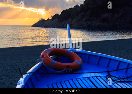 Boot auf den Strand von Bonassola mit Sonnenuntergang auf Madonnina della Punta Kirche. Loano, Ligurien, Italien. Stockfoto