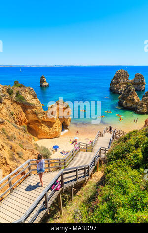 Nicht identifizierte junge Frau, Tourist, Foto von Praia do Camilo Strand von holzstufen, Algarve, Portugal Stockfoto