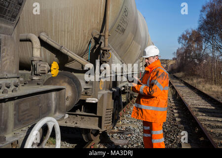 Ein Mitglied des Personals der Eisenbahnen in Gut sichtbare Kleidung Inspektion eine Eisenbahn Wagen bei einer geplanten Wartung Inspektion. Stockfoto