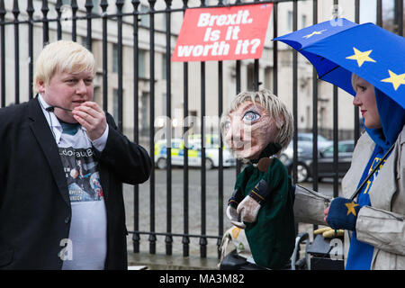 London, Großbritannien. 29. März, 2018. Boris Johnson Doppelgänger zeichnete Galdron und EU-Supergirl und Junge Europäerin des Jahres 2018 Madeleina Kay Protest mit einem Theresa May Marionette gegenüber von der Downing Street zum ersten Jahrestag der Auslösung der Artikel 50 und ein Jahr vor dem Beenden des Vereinigten Königreichs aus der Europäischen Union, oder Brexit zu markieren, wird festgelegt, stattfinden. Die Demonstranten verkleidet als "EU-Super Heroes' und 'Brexit Schurken'. Credit: Mark Kerrison/Alamy leben Nachrichten Stockfoto