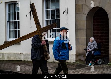 LEOMINSTER, HEREFORDSHIRE, UK - 30. März: Der Weg des Zeugnisses wird ein Mitglied der Öffentlichkeit saß in einem Rollstuhl als Mitglieder der christlichen Gemeinschaft in Leominster sammeln Teil in einer Karfreitagsprozession als Teil der Heiligen Woche und am 30. März 2018. Während der Wanderung von Zeugnis, das sie die symbolische Kreuz von der Baptist Church auf Etnam Street durch die mittelalterlichen Markt Marktplatz zum Kloster Kirche der Church Street, wo das Kreuz errichtet werden. Viele Städte und Dörfer schon halten Sie Spaziergänge oder Märsche des Zeugnisses als Zeichen ihrer gemeinsamen Glauben an den Tod und die Auferstehung Jesu Chr Stockfoto