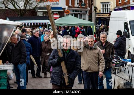 LEOMINSTER, HEREFORDSHIRE, UK - 30. März: Mitglieder von Leominster St Ethelbert der Kirche tragen das Kreuz durch die lokalen Freitag Markt in Mais Square als der christlichen Gemeinschaft in Leominster sammeln Teil in einer Karfreitagsprozession als Teil der Heiligen Woche und am 30. März 2018. Während der Wanderung von Zeugnis, das sie die symbolische Kreuz von der Baptist Church auf Etnam Street durch die mittelalterlichen Markt Marktplatz zum Kloster Kirche der Church Street, wo das Kreuz errichtet werden. Viele Städte und Dörfer schon halten Sie Spaziergänge oder Märsche des Zeugnisses als Zeichen ihrer gemeinsamen Glauben an den Tod und die Stockfoto