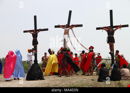 Cutud, Pampanga, Philippinen. 30 Mär, 2018. Ruben Enaje, ans Kreuz genagelt, die Schauspieler spielen als römische Soldaten in Cutud angehoben. Karfreitag Kreuzigung Rechte wurden in Cutud, Pampanga während der jährlichen Maleldo Heilige Woche Feier statt. Credit: J Gerard Seguia/ZUMA Draht/Alamy leben Nachrichten Stockfoto