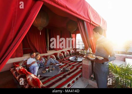 Ein paar und ein Kellner auf der Dachterrasse des Riad AnaYela Hotels (Marrakesch, Marokko) Stockfoto