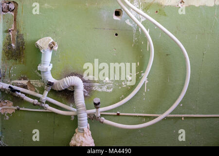 Wasser- und Abwasserleitungen auf dem Hintergrund der alten Mauer. Reparatur im Haus. Verbindung von Metall - Kunststoff Rohre Stockfoto