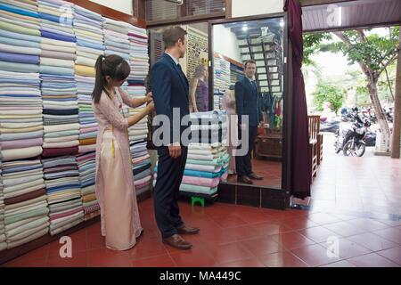 Ein Mann, der versucht, auf eine Klage bei den 'Bebe anpassen" Shop in Hoi An, Vietnam Stockfoto