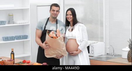 Mann und die schwangere Frau mit einem Paket von baguettes in der Küche stehend Stockfoto