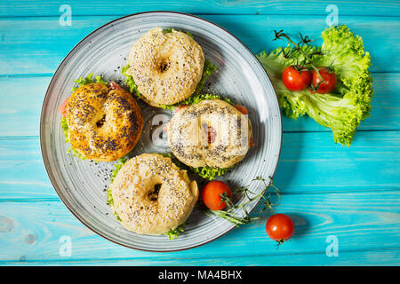 Bagel mit Lachs, Gemüse, Sahne und Käse auf Blau Holz Hintergrund. Ansicht von oben Stockfoto