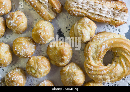 Eine Regelung von cremig Gebäck auf einem weißen Tischtuch. Stockfoto