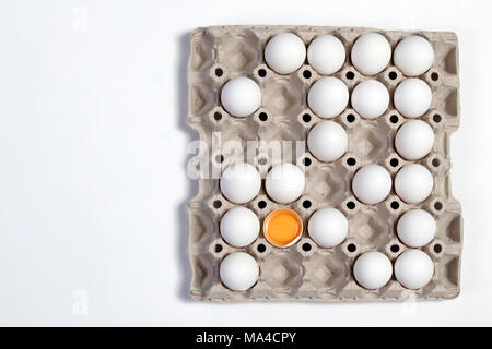 Die gebrochene Eier mit der anderen weißen Eier im Karton aus dem Store. Es sieht aus wie ein Schachbrett. Stockfoto