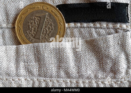 Türkische Münze mit einer Stückelung von einer Lira in der Tasche des alten Leinen Hose leeren schwarzen Streifen für Label Stockfoto
